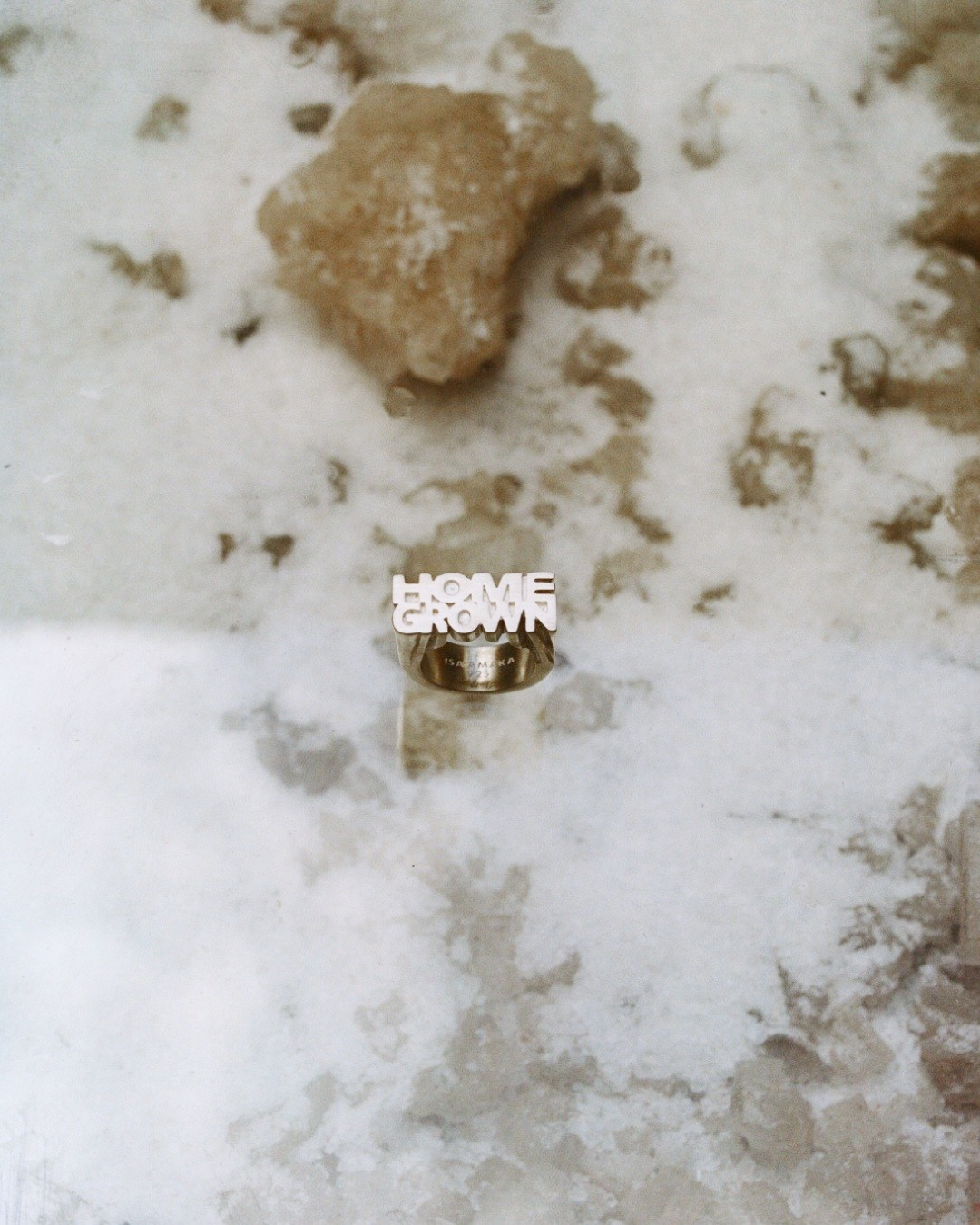 Silver ring with 'Home Grown' text on a textured surface